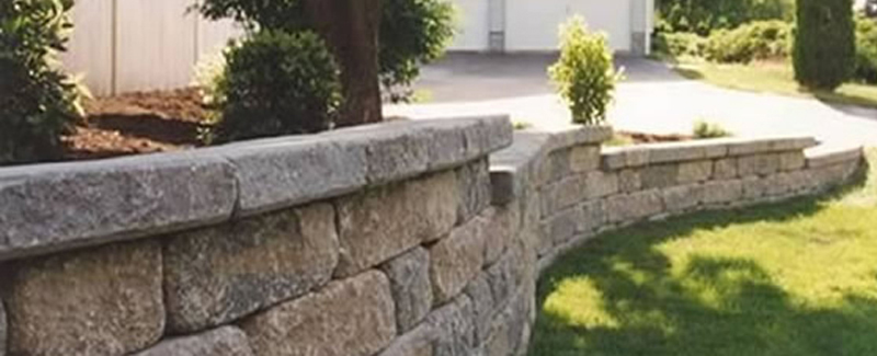 A long, winding retaining wall streching around a beautiful backyard.